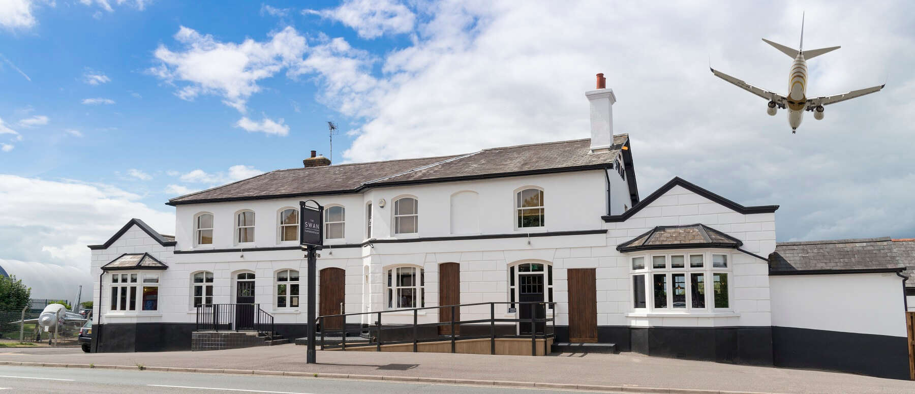 external view of pub with blue sky and aeroplane above